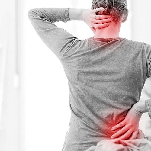A person holding their neck and lower back with red pain highlights, showing neck and back pain from muscle tension.