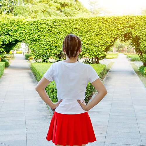 Woman standing at a forked garden path, symbolizing the choice to break old generational parenting patterns.