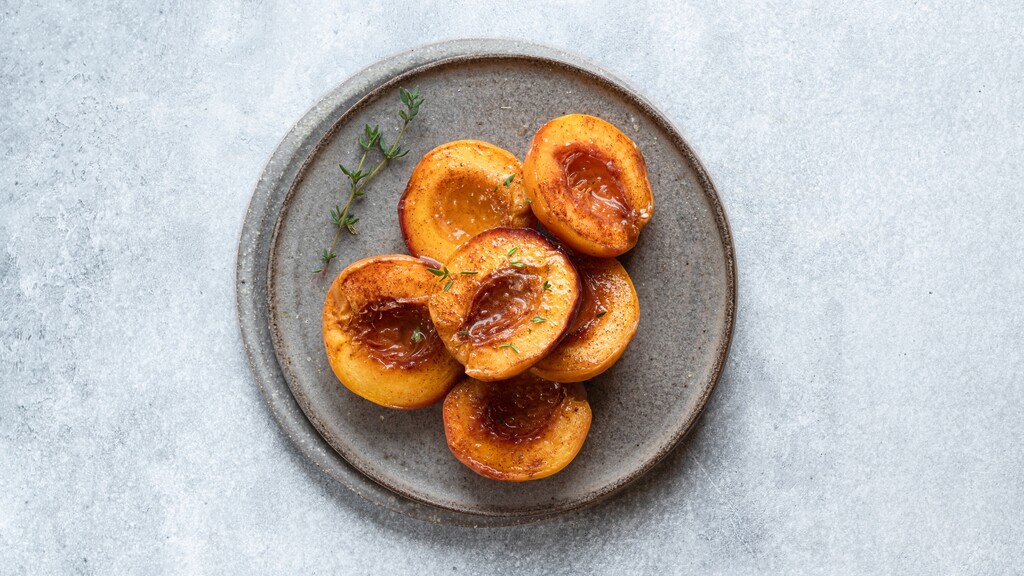 Baked peach halves with cinnamon on a plate.