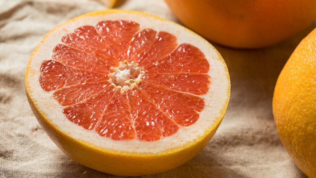 Halved ruby grapefruit showing the pink flesh and thick peel.