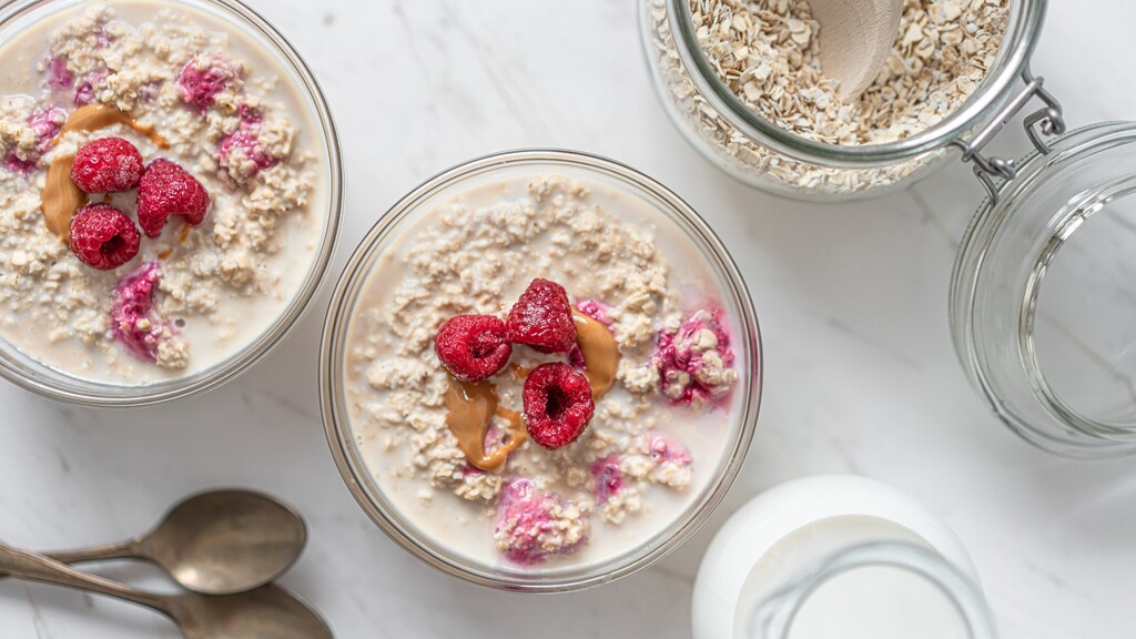 Overnight oats with raspberries and peanut butter in glass jars.