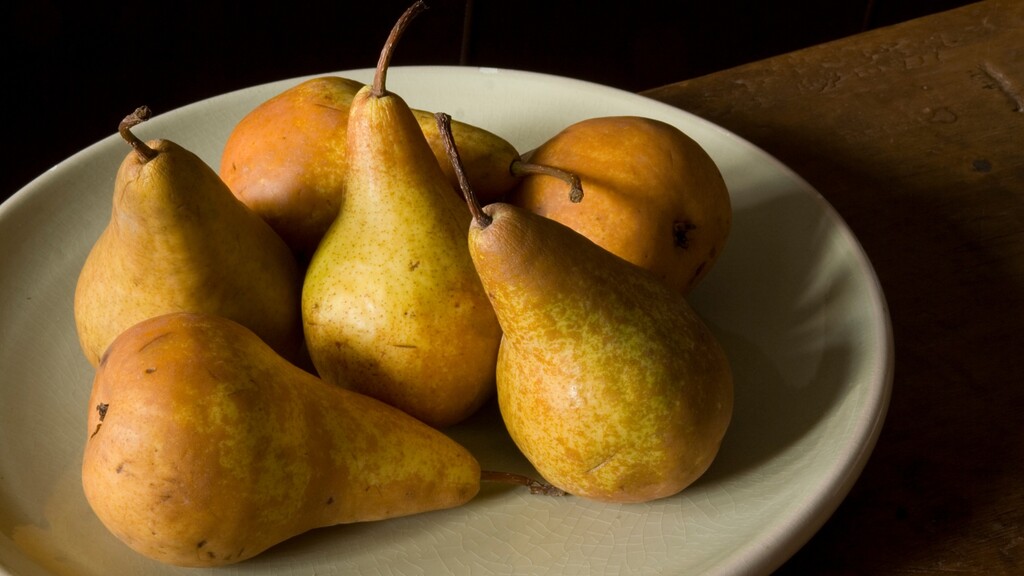 Fresh pears arranged on a shallow bowl.