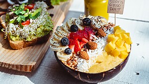 Colorful smoothie bowl with banana, strawberries, mango, coconut, almonds, and chia seeds.