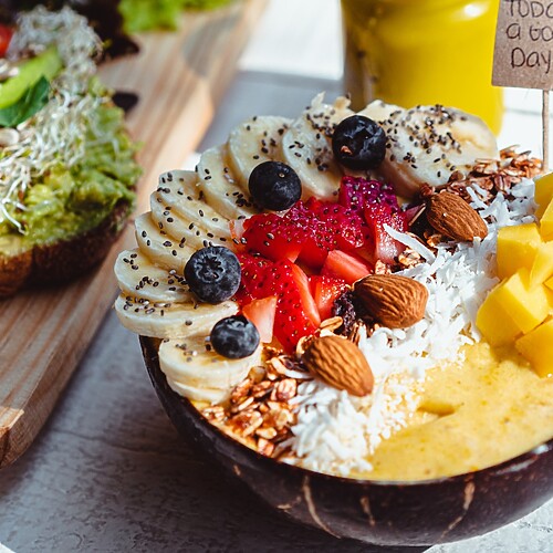 Colorful smoothie bowl with banana, strawberries, mango, coconut, almonds, and chia seeds.