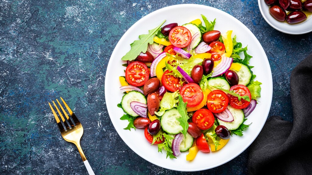 Mediterranean salad with Kalamata olives, tomatoes, cucumber, peppers, onions, and leafy greens.