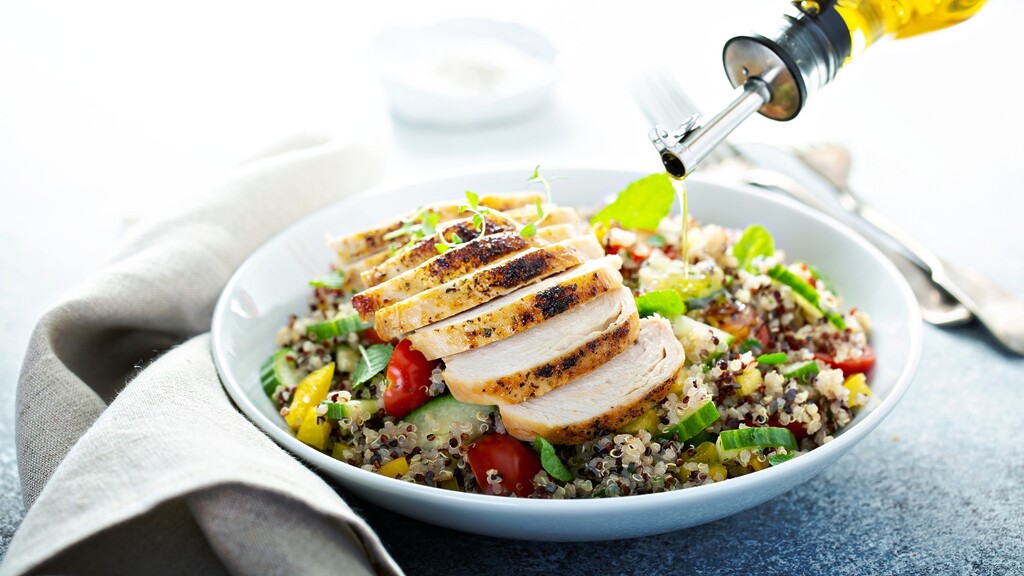 Mediterranean chicken quinoa bowl with cucumber, tomatoes, herbs, and olive oil dressing.
