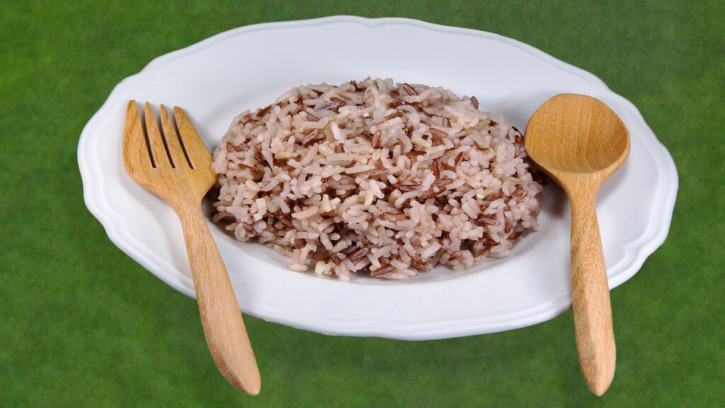 Mixed white and brown rice served on a white plate with wooden utensils.