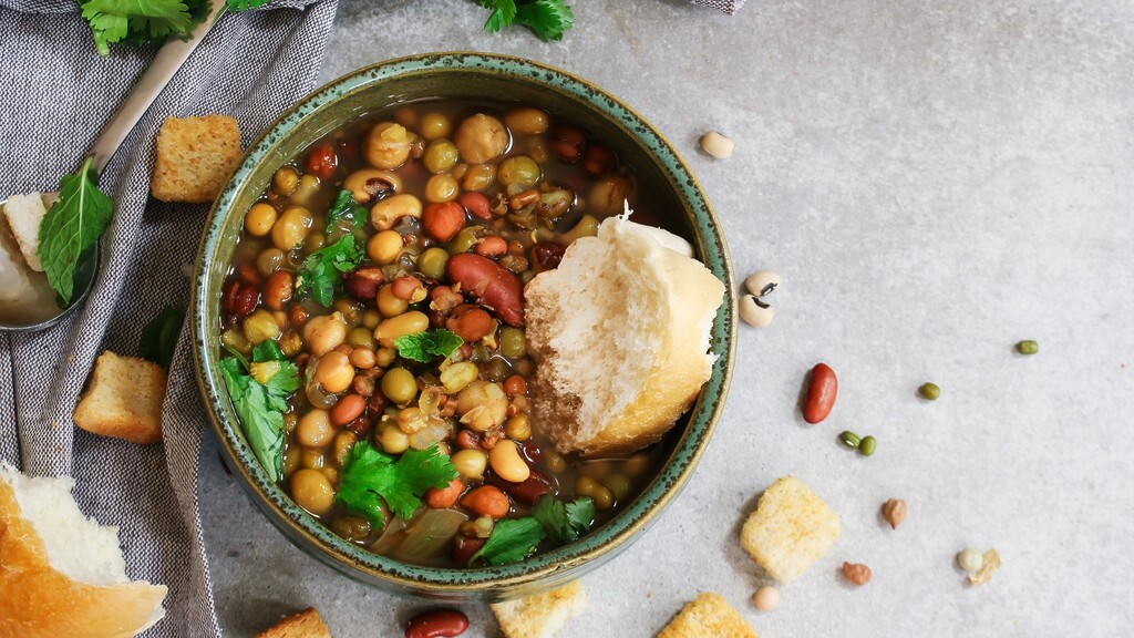 Mixed bean and lentil soup topped with herbs and served with bread.