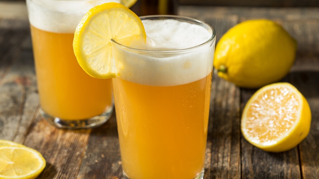 Kombucha shandy with lemon garnish served in tall beer glasses.